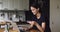 Woman standing in kitchen holding card using computer makes purchase