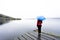 Woman standing at lake keeping umbrella under the rain