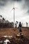 Woman standing and looking on  wind turbine station in destroyed and deforested forest on tree stump in bad weather conditions -