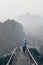 Woman standing on mountain peak with stairs going down during sunrise foggy morning in Hpa-An, Myanmar