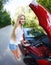 Woman standing near the opened hood of the broken cabriolet