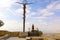 Woman standing next to The Brazen Serpent, religions christian cross, overlooking the promised and holy land in the distance