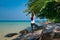 A woman standing on one leg while practicing yoga on wooden bridge over the sea during summer vacation. attractive Asian woman