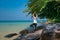 A woman standing on one leg while practicing yoga on wooden bridge over the sea during summer vacation. attractive young Asian