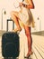 Woman standing one leg on suitcase, summertime