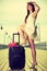 Woman standing one leg on suitcase, summertime