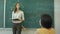 Woman standing over green chalkboard at the classroom