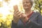 Woman standing in park typing on smart phone. Focus is o