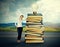 Woman standing by pile of old books with bright light bulb on top of it