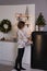 A woman standing at a refrigerator in christmas decorated room