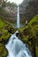 A woman standing on the rock at Beautiful falls in forest, West coast USA. Watson Falls is waterfall on Watson Creek.