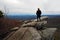 Woman standing on rock outcropping looking over layered mountains near Blowing Rock, North Carolina.