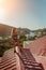 Woman standing on rooftop, enjoys town view and sea mountains. Peaceful rooftop relaxation. Below her, there is a town