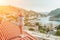 Woman standing on rooftop, enjoys town view and sea mountains. Peaceful rooftop relaxation. Below her, there is a town