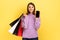 Woman standing with satisfied look showing shopping bags and smart phone with blank screen for ad.