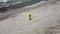 Woman is standing on the shore of the ocean and waving hand to drone camera filming her