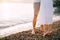 Woman is standing on tiptoe next to man on a pebbly beach. Cropped. Faceless