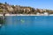 A woman standing up on paddle board rowing across the vast deep blue ocean water in the Dana Point Harbor surrounded by buoys