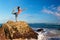 Woman standing in yoga pose on sea beach rock