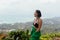 Woman stands admiring the view of a lush, coastal landscape from a high vantage point