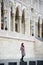 Woman stands against the backdrop of powerful European architectural structure