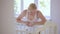 A woman stands at a baby crib and admires her little sleeping baby