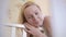 A woman stands at a baby crib and admires her little sleeping baby