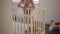 A woman stands at a baby crib and admires her little sleeping baby