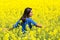 Woman stands in blooming yellow rapeseed field