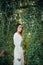 Woman stands on a bridge entwined with lianas in orangery