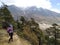 Woman stands with a camera on the pathway with mountain in the background