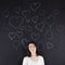 Woman stands beside a chalkboard adorned with hand-drawn hearts