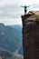 Woman stands on a cliff spreading her arms at Preikestolen rock, Norway