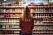 A woman stands confidently in front of a neatly arranged display of assorted jars, showcasing their variety and quality, woman