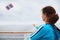 Woman stands on cruise liner deck and flies kite