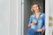 Woman stands in the doorway of the bedroom with a glass of cappuccino in her hand