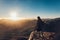 Woman stands on edge of cliff on Mount Sinai against background of sunrise.