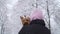 Woman stands with her back to camera with head covered a hood holding small yorkshire terrier wrapped in a blue blanket