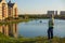 Woman stands on hill and looks at beauty of amazing pictorial landscape of European style city with buildings and lake