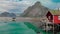 Woman stands on house terrace over sea against rocky hills