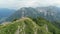 Woman stands on mountain peak and raises arms enjoying freedom. Aerial view