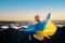 A woman stands with the national Ukrainian flag and waving it praying for peace at sunset in Lviv..A symbol of the Ukrainian