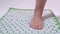 Woman stands with one foot on an acupuncture massage mat. Close-up.