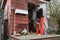 Woman stands outside chicken coop holding eggs in a basket