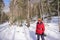 Woman stands on sunny snowshoe trail in winter