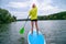A woman stands on a SUP board on a large river on a cloudy day. Stand on the oars - great outdoor recreation