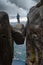 Woman stands on top of large boulder, Visiting Norway Kjeragbolten located south of Lysefjorden