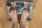 A woman stands with two feet on a scale. Overweight concept