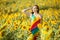 Woman stands on the yellow field of sunflowers.