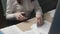 Woman staples papers sitting at table in office closeup